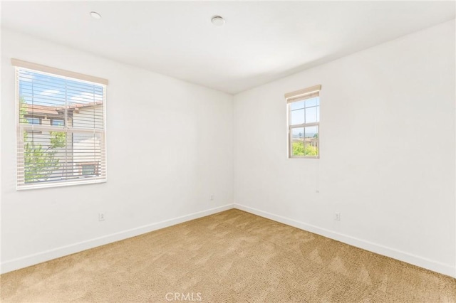 unfurnished room with baseboards and light colored carpet