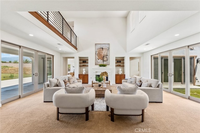 carpeted living room featuring french doors, a towering ceiling, and built in features