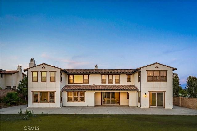 rear view of property featuring fence, a patio, a tile roof, stucco siding, and a yard