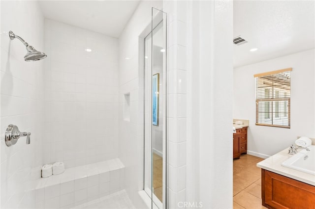 bathroom with tile patterned flooring, vanity, and a tile shower