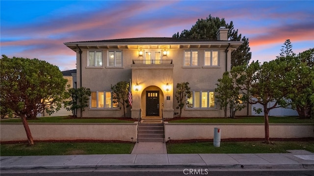 view of front of house with a yard and a balcony