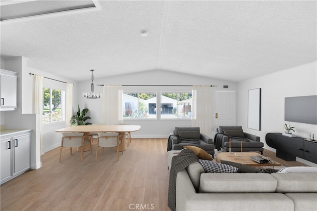 living area featuring lofted ceiling, a healthy amount of sunlight, a textured ceiling, and light wood finished floors