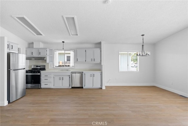 kitchen with lofted ceiling, light wood-style flooring, under cabinet range hood, stainless steel appliances, and a sink