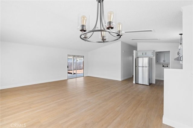 unfurnished dining area with a chandelier, baseboards, and light wood-style floors