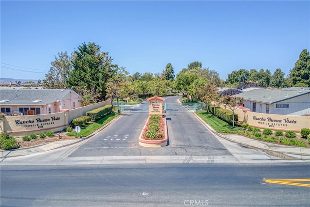 view of road featuring a residential view, sidewalks, curbs, and a gated entry