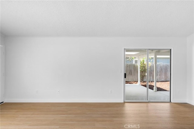 spare room with light wood-style flooring, baseboards, and a textured ceiling