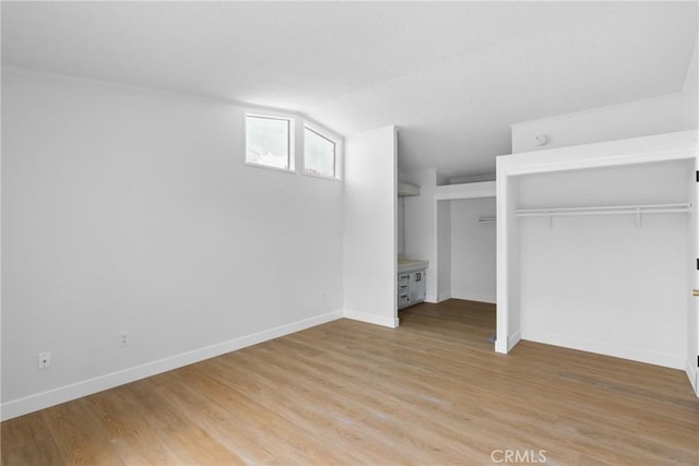 unfurnished bedroom featuring lofted ceiling, light wood-type flooring, and baseboards