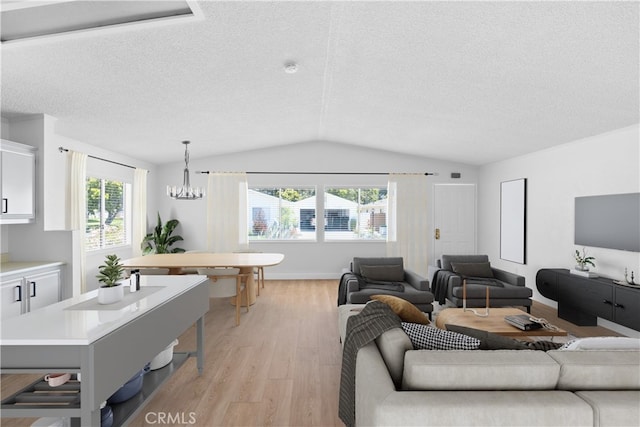 living area featuring light wood-type flooring, plenty of natural light, vaulted ceiling, and a textured ceiling