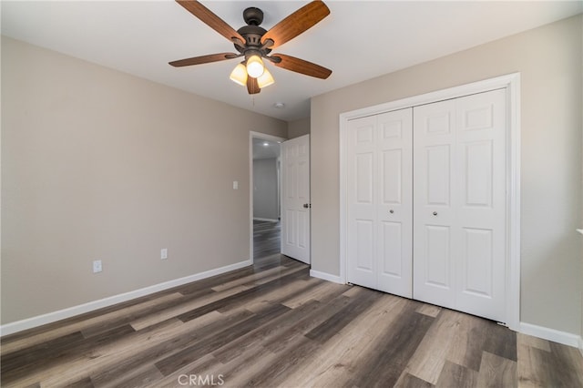 unfurnished bedroom featuring dark hardwood / wood-style flooring, ceiling fan, and a closet