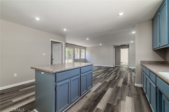 kitchen featuring dark wood-type flooring, a center island, and blue cabinetry