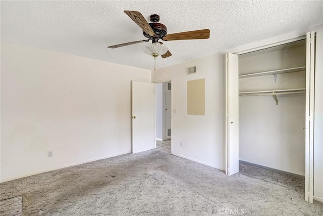 unfurnished bedroom featuring ceiling fan, a textured ceiling, a closet, and light carpet