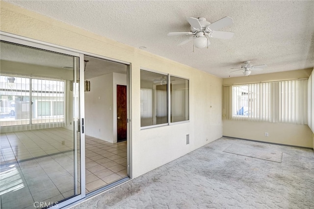 empty room featuring ceiling fan, light colored carpet, and a textured ceiling