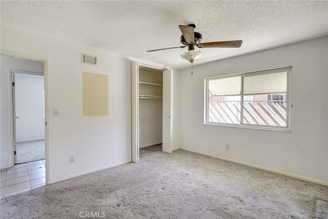 unfurnished bedroom with ceiling fan, a textured ceiling, and light carpet