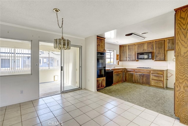 kitchen featuring a textured ceiling, decorative light fixtures, black appliances, light colored carpet, and an inviting chandelier