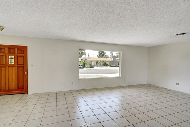 tiled empty room featuring a textured ceiling