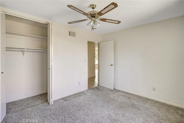 unfurnished bedroom featuring a closet, ceiling fan, light colored carpet, and a textured ceiling