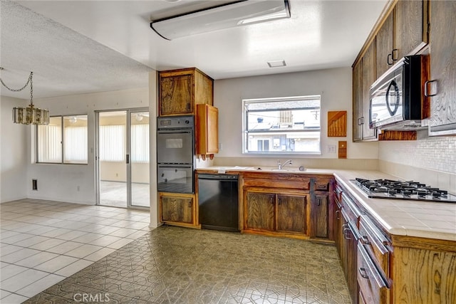 kitchen featuring tasteful backsplash, sink, hanging light fixtures, black appliances, and light tile patterned floors