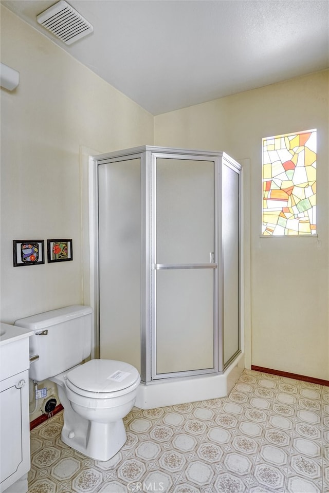 bathroom featuring vanity, toilet, and a shower with door