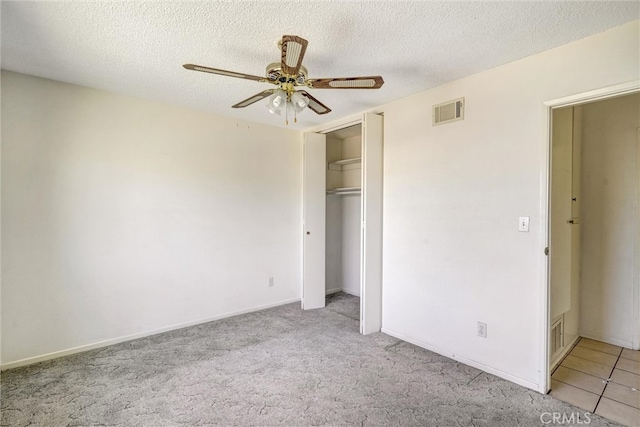 unfurnished bedroom with light carpet, ceiling fan, and a textured ceiling