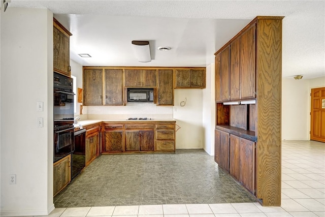 kitchen featuring a textured ceiling, light tile patterned floors, and black appliances