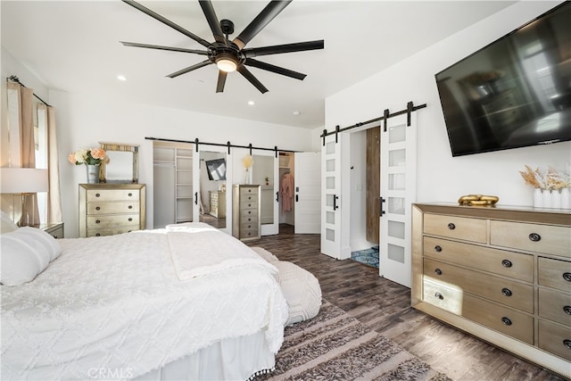 bedroom featuring dark wood-type flooring, a barn door, and ceiling fan