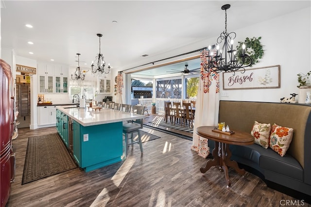 kitchen featuring white cabinetry, dark wood-type flooring, pendant lighting, and an island with sink