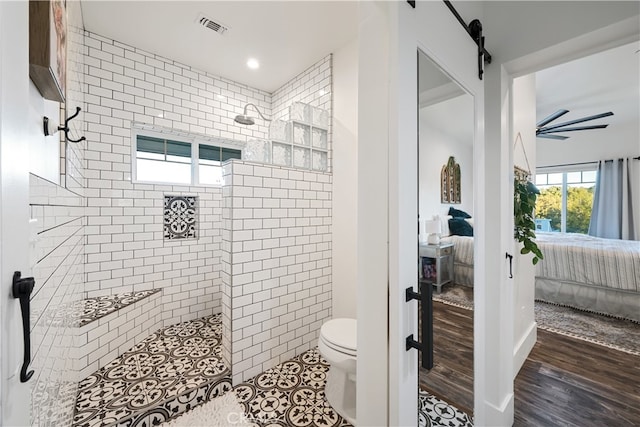 bathroom with a tile shower, hardwood / wood-style flooring, and toilet