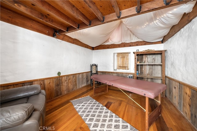 recreation room with wood walls, beam ceiling, and hardwood / wood-style floors