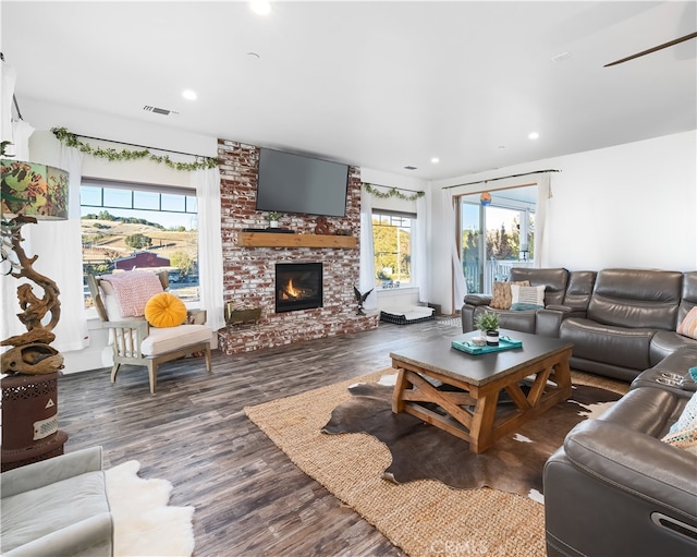 living room with a fireplace, dark hardwood / wood-style floors, and a healthy amount of sunlight