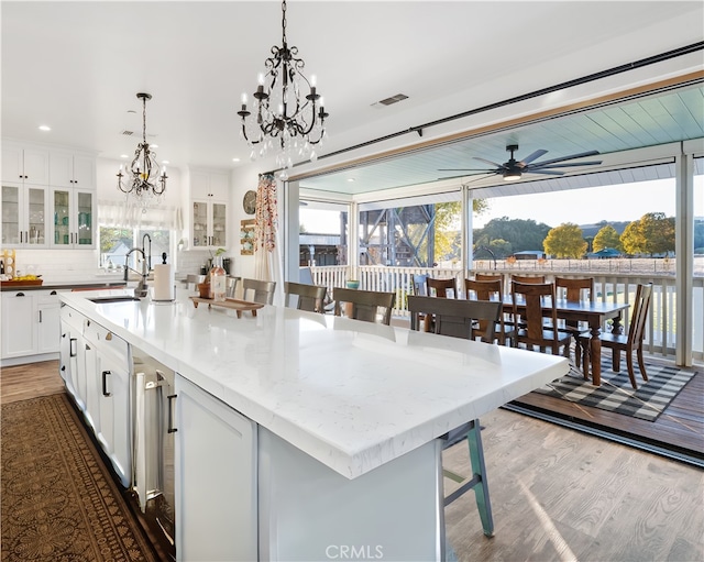 kitchen featuring a breakfast bar area, dark wood-type flooring, backsplash, a center island with sink, and sink