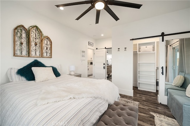 bedroom featuring a closet, a walk in closet, a barn door, and ceiling fan