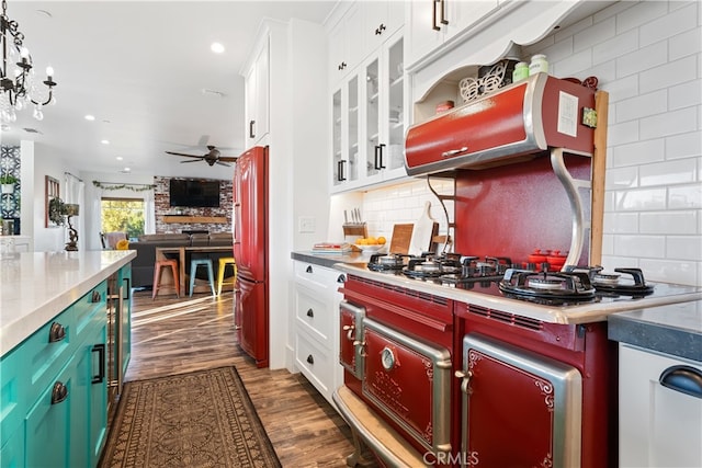 kitchen featuring ceiling fan with notable chandelier, backsplash, white cabinetry, decorative light fixtures, and dark hardwood / wood-style floors