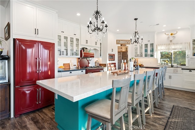 kitchen featuring white cabinetry, dark wood-type flooring, decorative backsplash, and a center island with sink