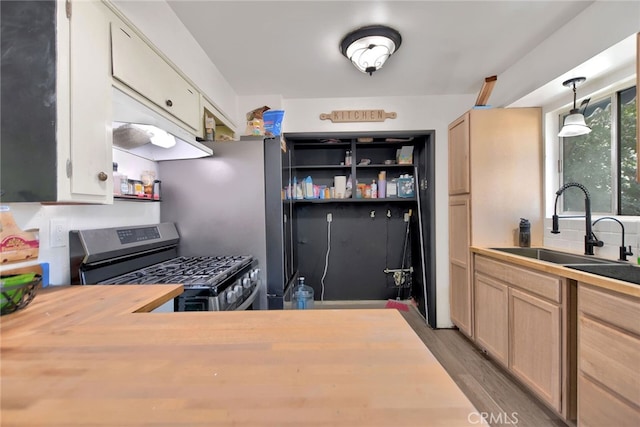 kitchen featuring pendant lighting, hardwood / wood-style flooring, sink, butcher block counters, and stainless steel gas stove