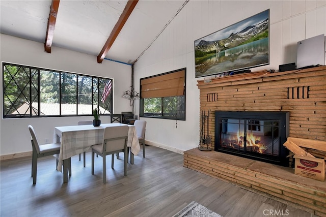 dining space featuring wood-type flooring and vaulted ceiling with beams