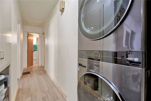 laundry area with stacked washer / dryer and light hardwood / wood-style floors