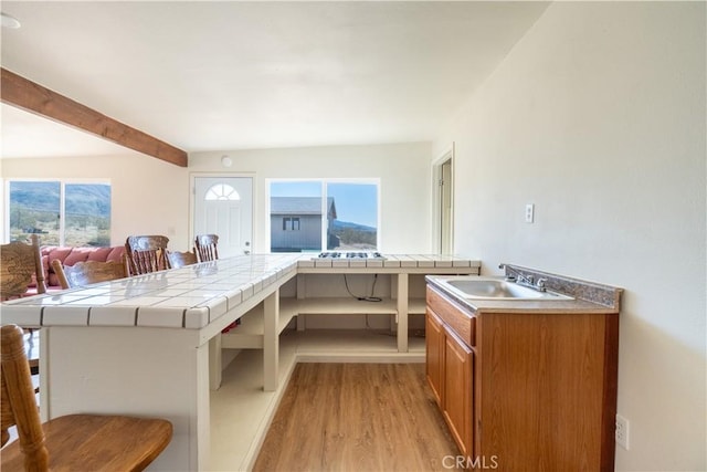 50471 Cholla Rd, Johnson Valley, CA 92285 - interior space with brown cabinets, tile countertops, a sink, beamed ceiling, and light wood-style flooring