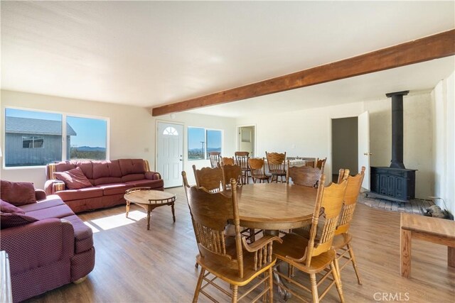 50471 Cholla Rd, Johnson Valley, CA 92285 - dining area featuring beamed ceiling, light wood-style floors, a wood stove, and a wealth of natural light