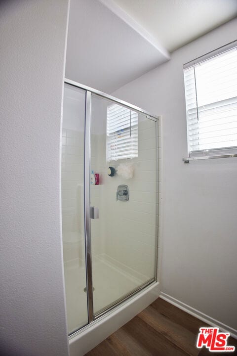 bathroom with wood-type flooring and an enclosed shower