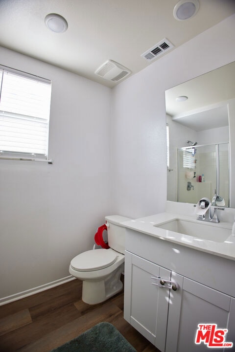 bathroom featuring vanity, toilet, walk in shower, and wood-type flooring