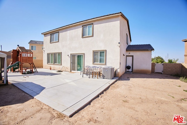 back of property with central AC, a patio area, and a playground