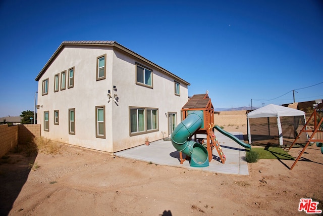 rear view of house with a patio and a playground