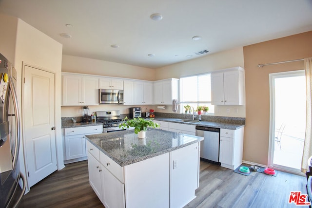 kitchen with appliances with stainless steel finishes, white cabinetry, and hardwood / wood-style flooring