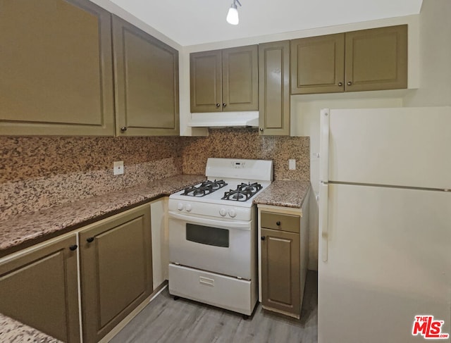 kitchen featuring light stone counters, light wood-type flooring, white appliances, and decorative backsplash