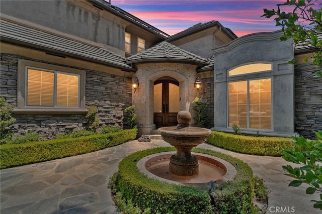 exterior entry at dusk featuring a patio