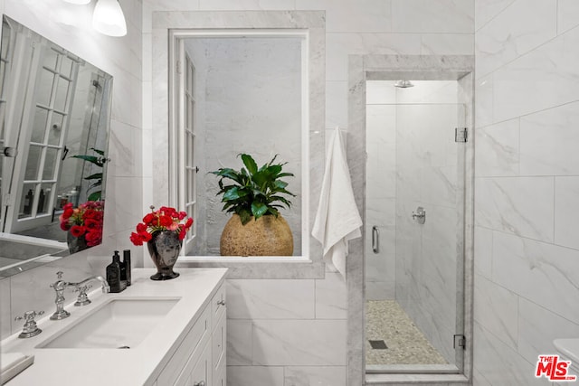 bathroom featuring an enclosed shower, vanity, tasteful backsplash, and tile walls