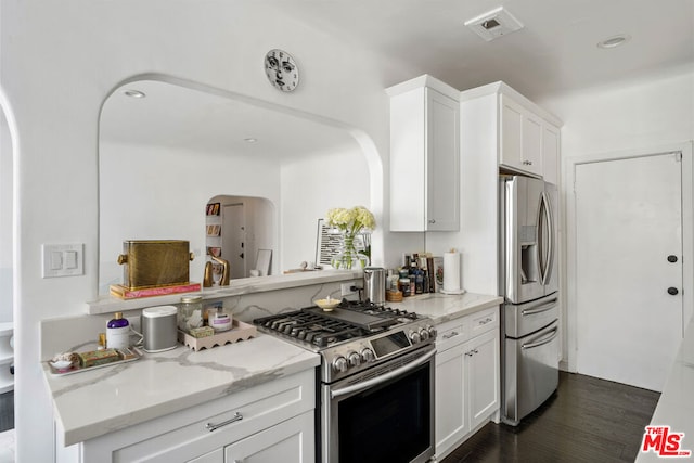 kitchen featuring appliances with stainless steel finishes, dark hardwood / wood-style flooring, white cabinetry, and light stone counters