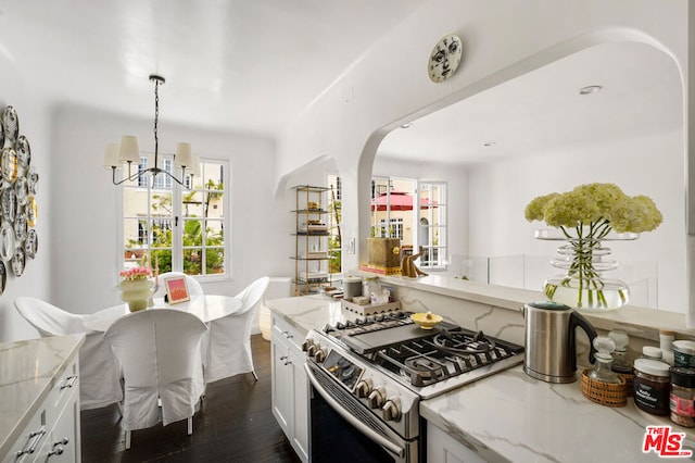 kitchen with decorative light fixtures, white cabinetry, dark wood-type flooring, and stainless steel gas range