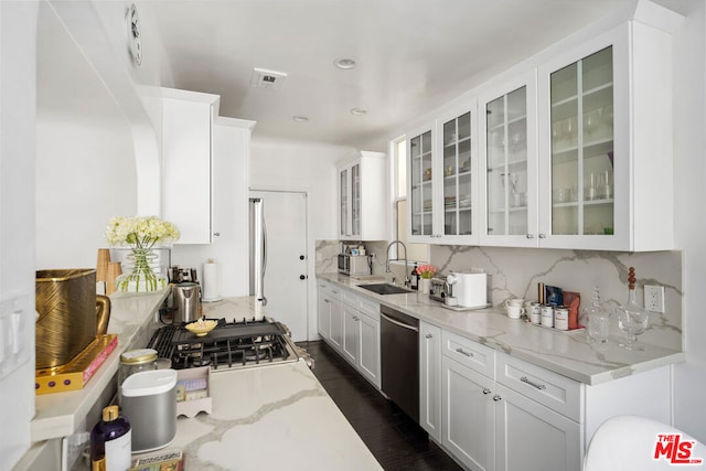 kitchen featuring backsplash, light stone countertops, sink, and appliances with stainless steel finishes