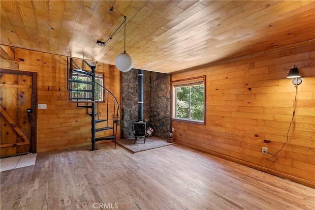 interior space with wooden ceiling, a wood stove, and wood walls